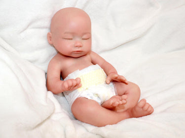 Full silicone reborn baby doll 13 inches with closed eyes, bald head, and diaper, realistic preemie newborn doll on white blanket